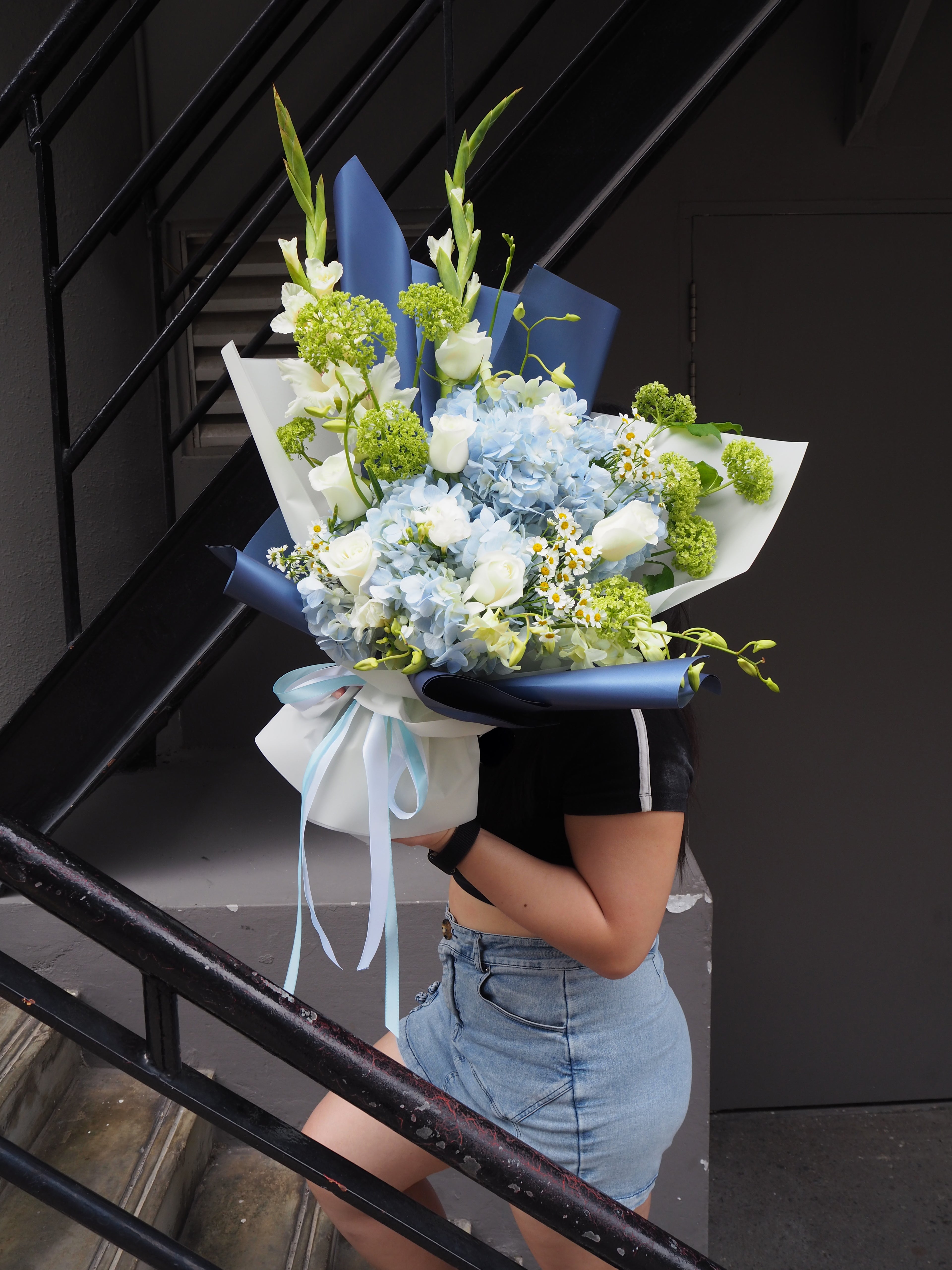 Person holding a bouquet of flowers against a black background