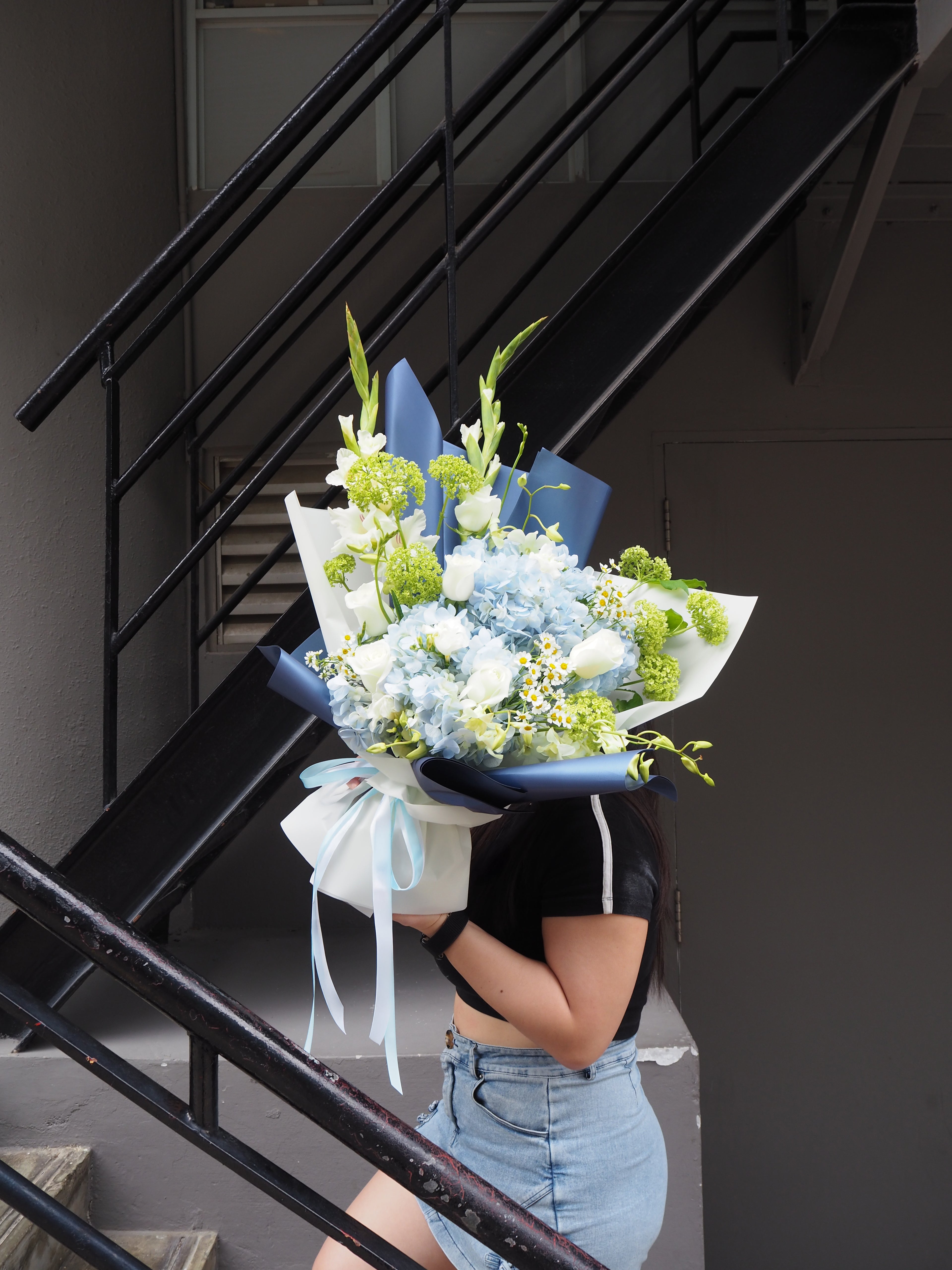 Person holding a bouquet of flowers against a staircase background