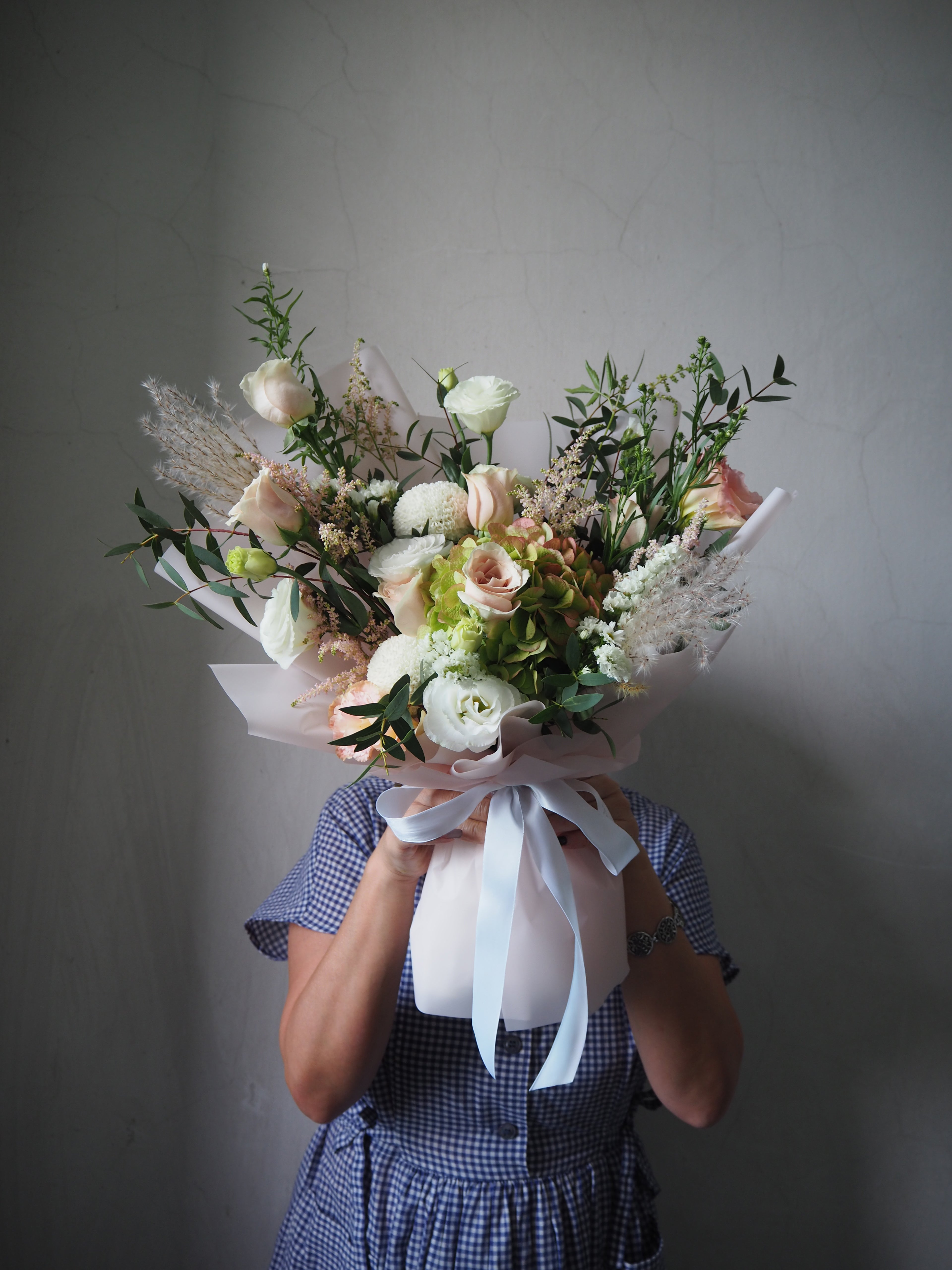 Person holding a bouquet of flowers against a plain background
