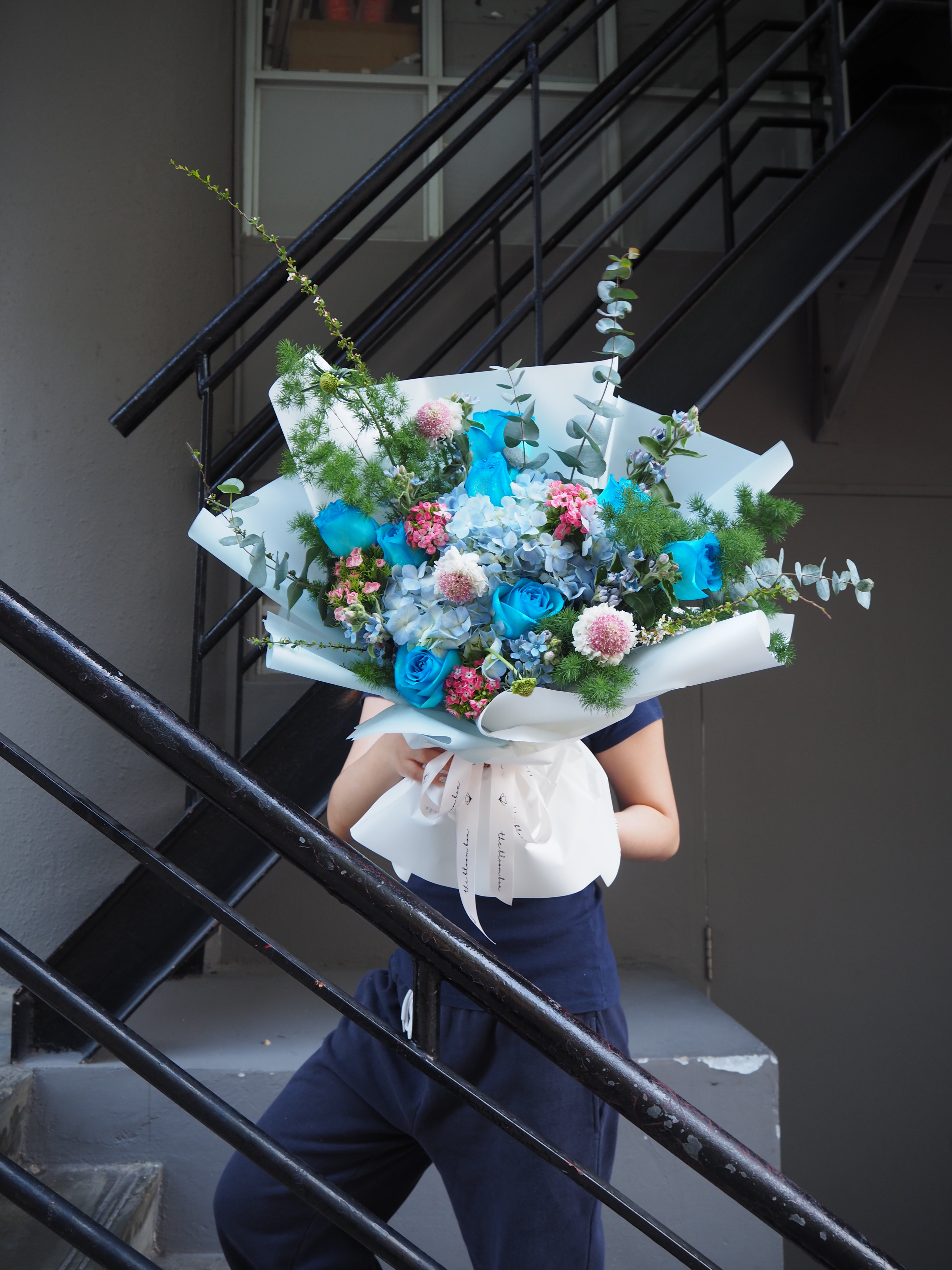 A grand fresh flower bouquet of blue hydranges with blue roses on a staircase