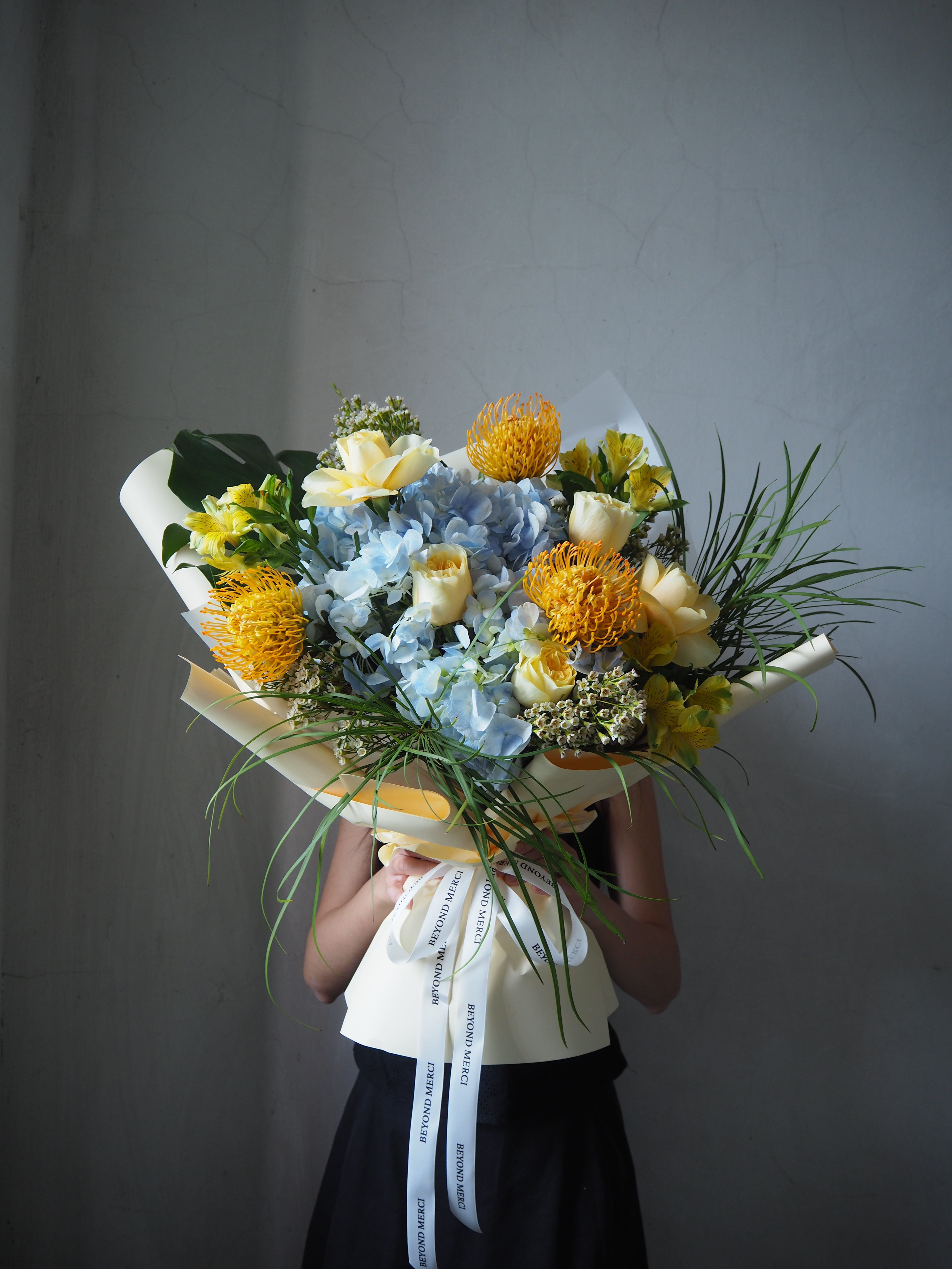 A premium fresh flower creation of blue and yellow flowers by Beyond Merci florist.