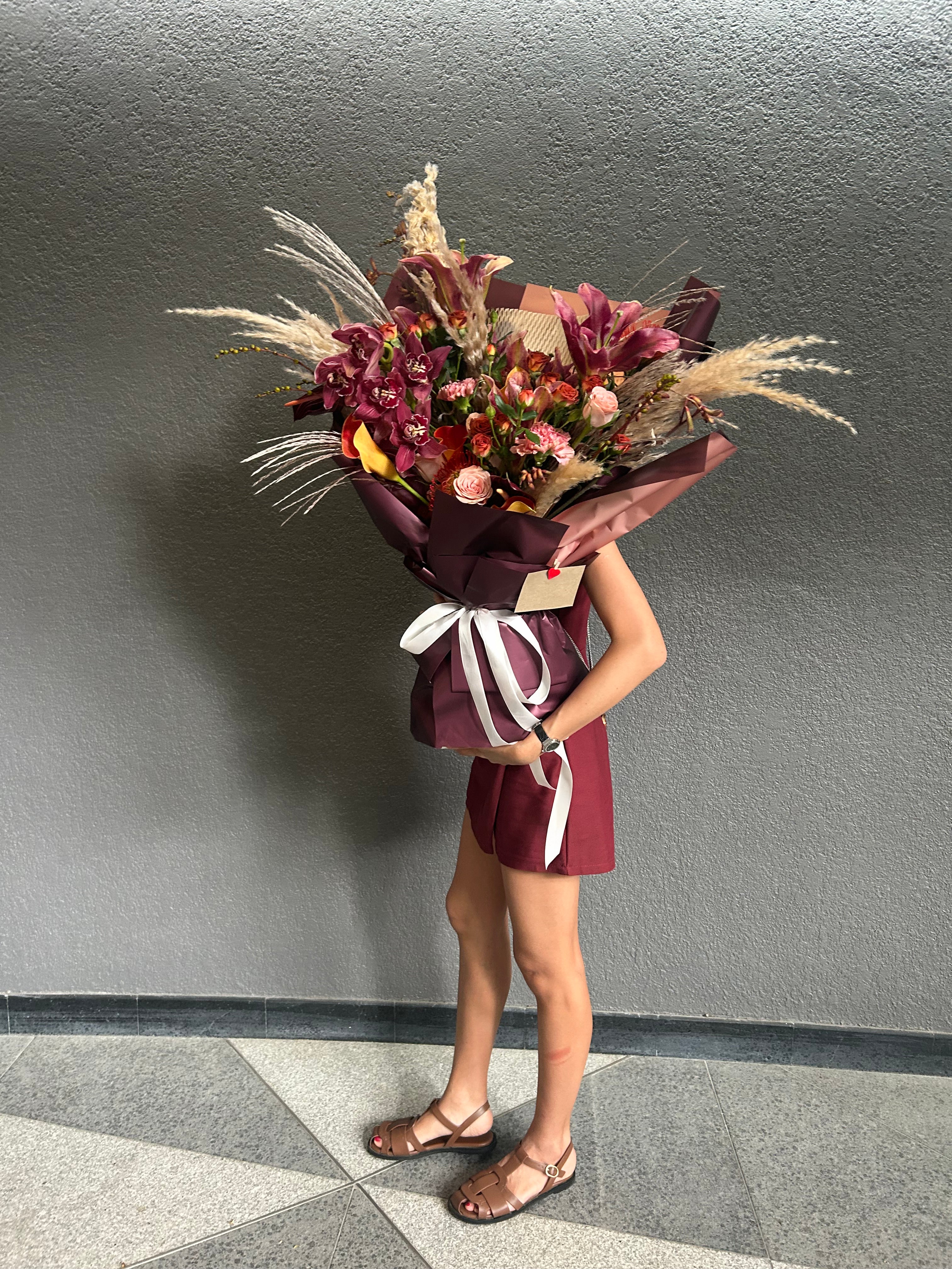 Person holding a bouquet of flowers against a gray wall