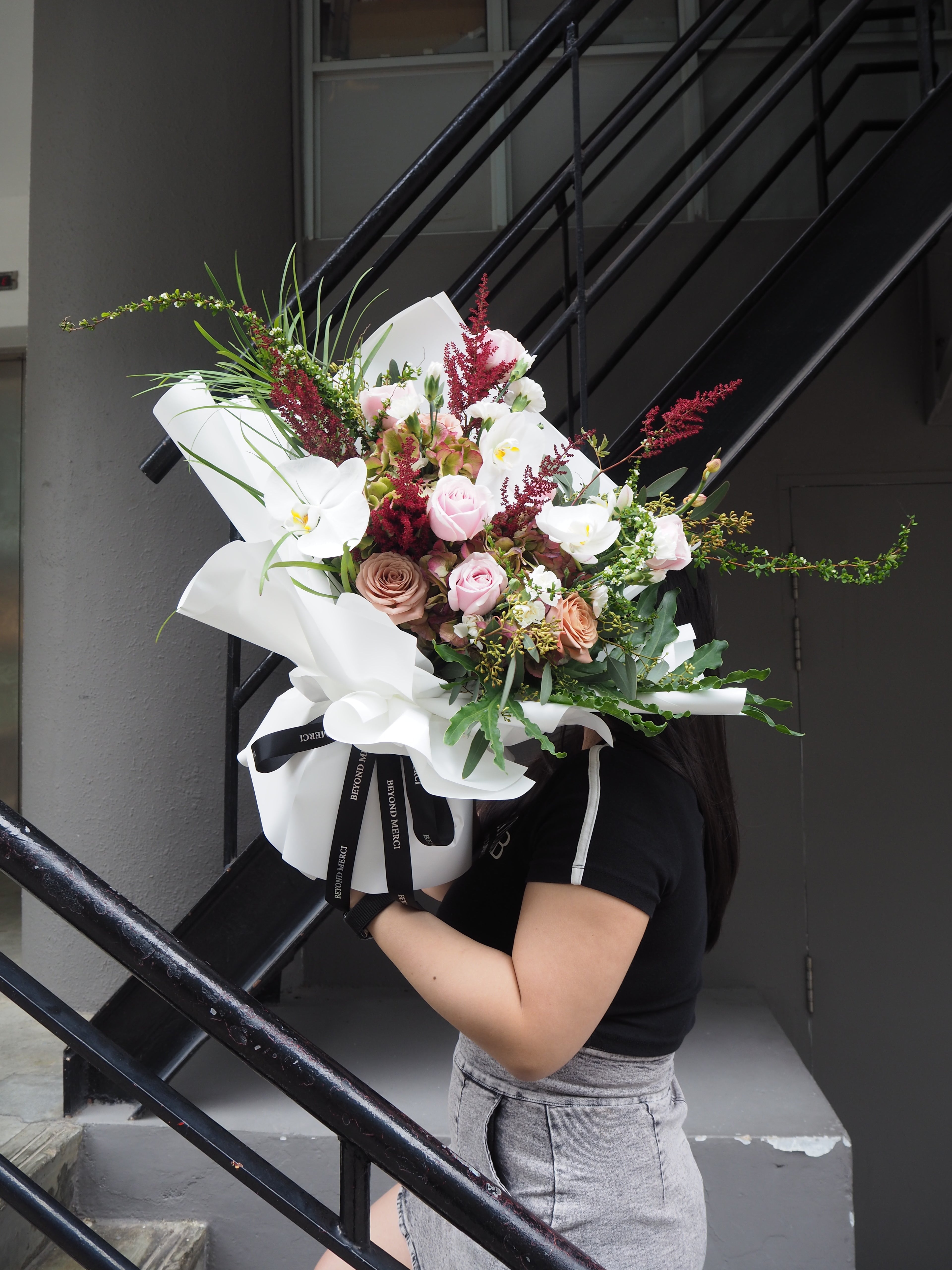 Person holding a large bouquet of flowers on a staircase