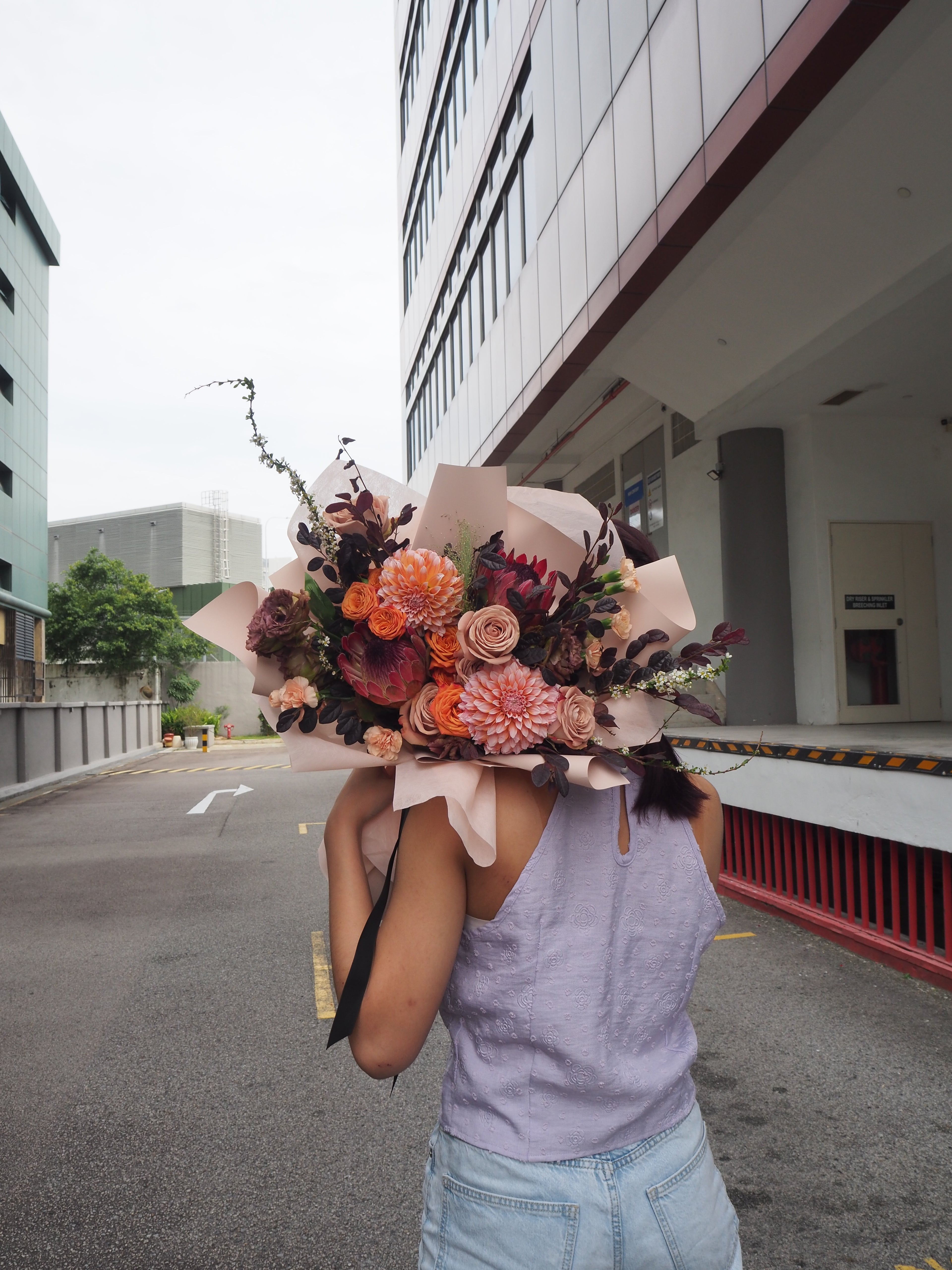 A mix of red protea and pink dahlia with deep red flowers curated by Beyond Merci premium florist.