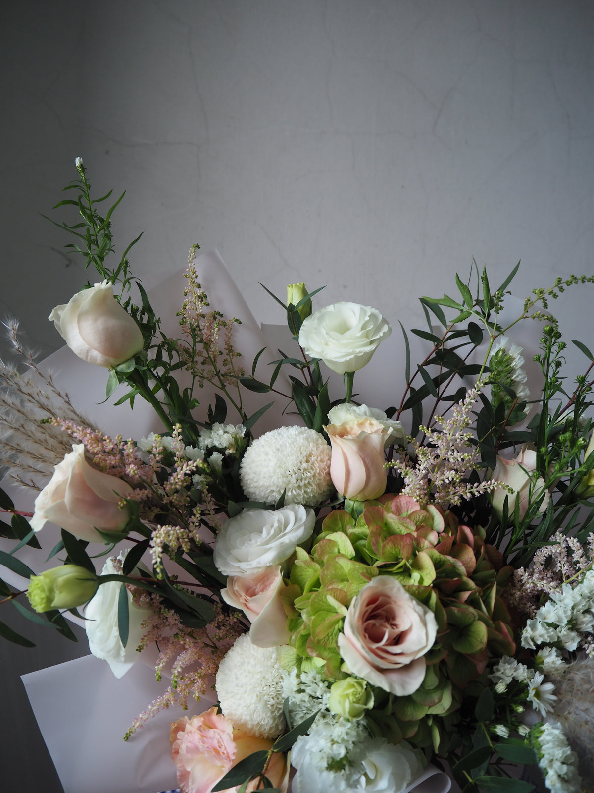 A close up of fresh flower bouquet of green hydrangea mix with pink astilbe, pale pink rose. 
