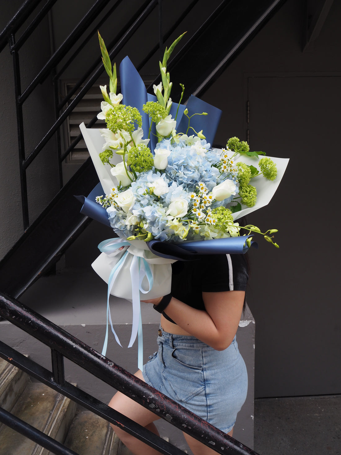 Person holding a bouquet of flowers against a black background