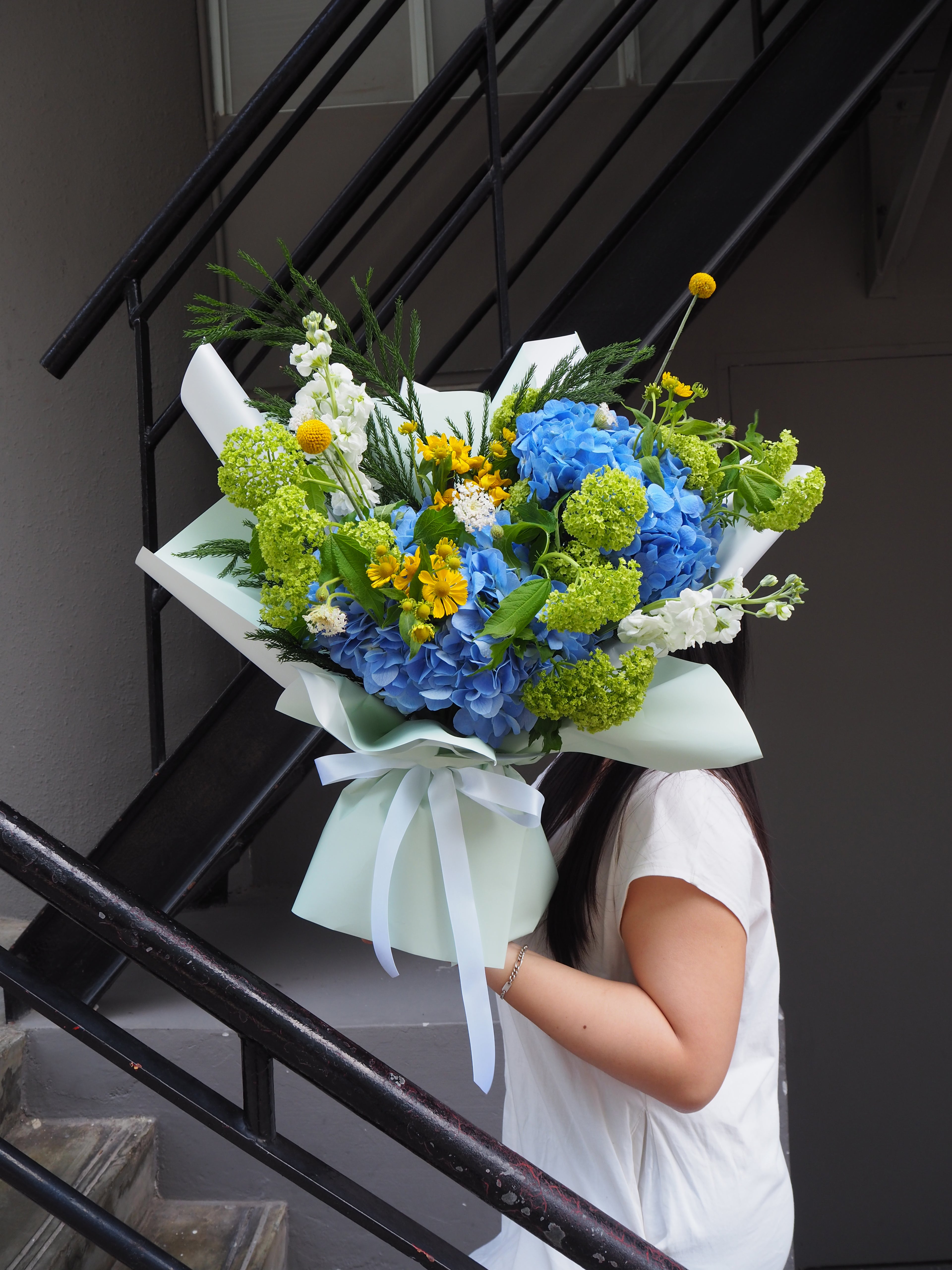 Person holding a bouquet of flowers on a staircase