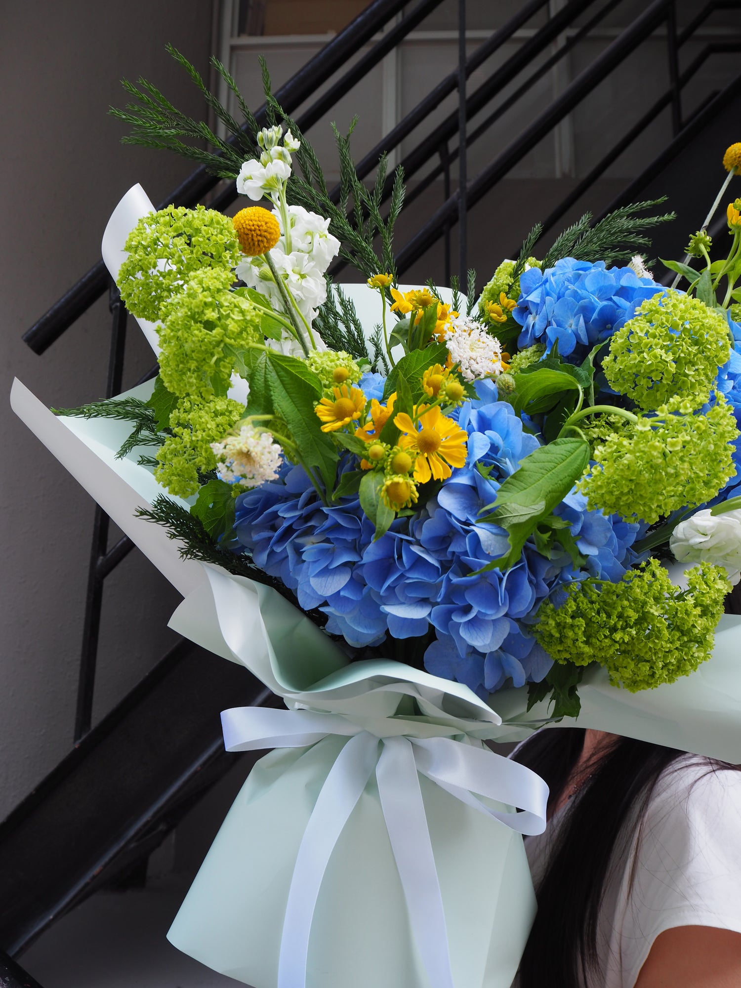 Bouquet of flowers with blue, green, and yellow colors on a neutral background