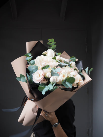 Bouquet of white flowers in brown paper packaging on a dark surface