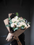 Bouquet of white flowers in brown paper packaging on a dark surface