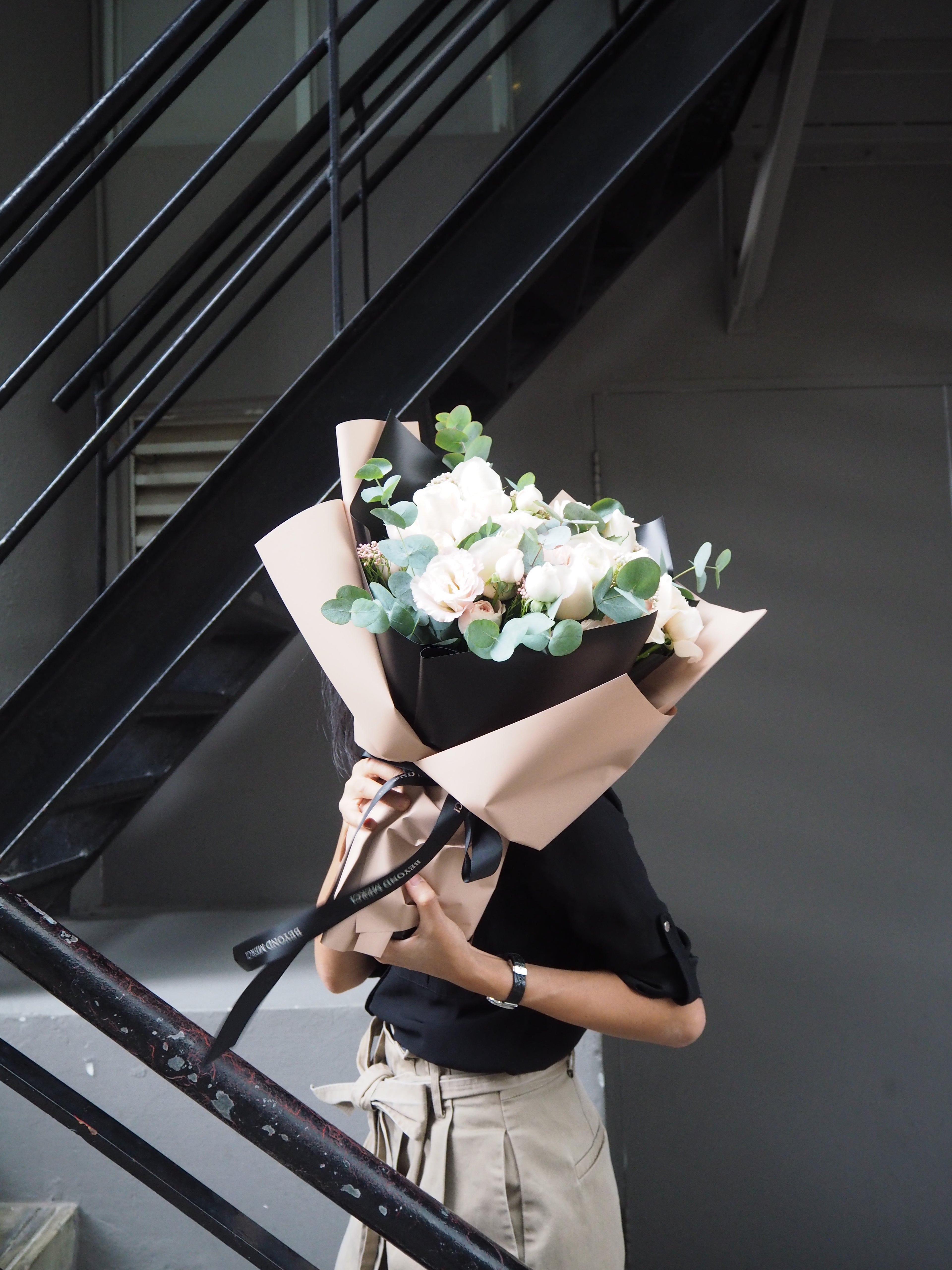 Person standing on stairs rwith a bouquet of flowers.