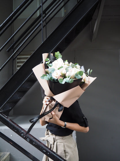Person standing on stairs rwith a bouquet of flowers.
