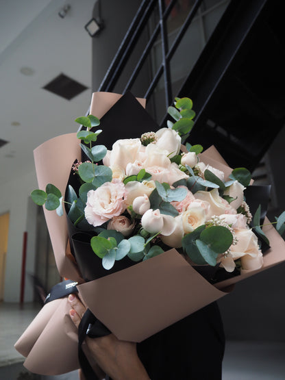 Bouquet of flowers wrapped in brown paper held by a person indoors.