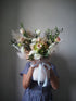 Person holding a bouquet of flowers against a plain background