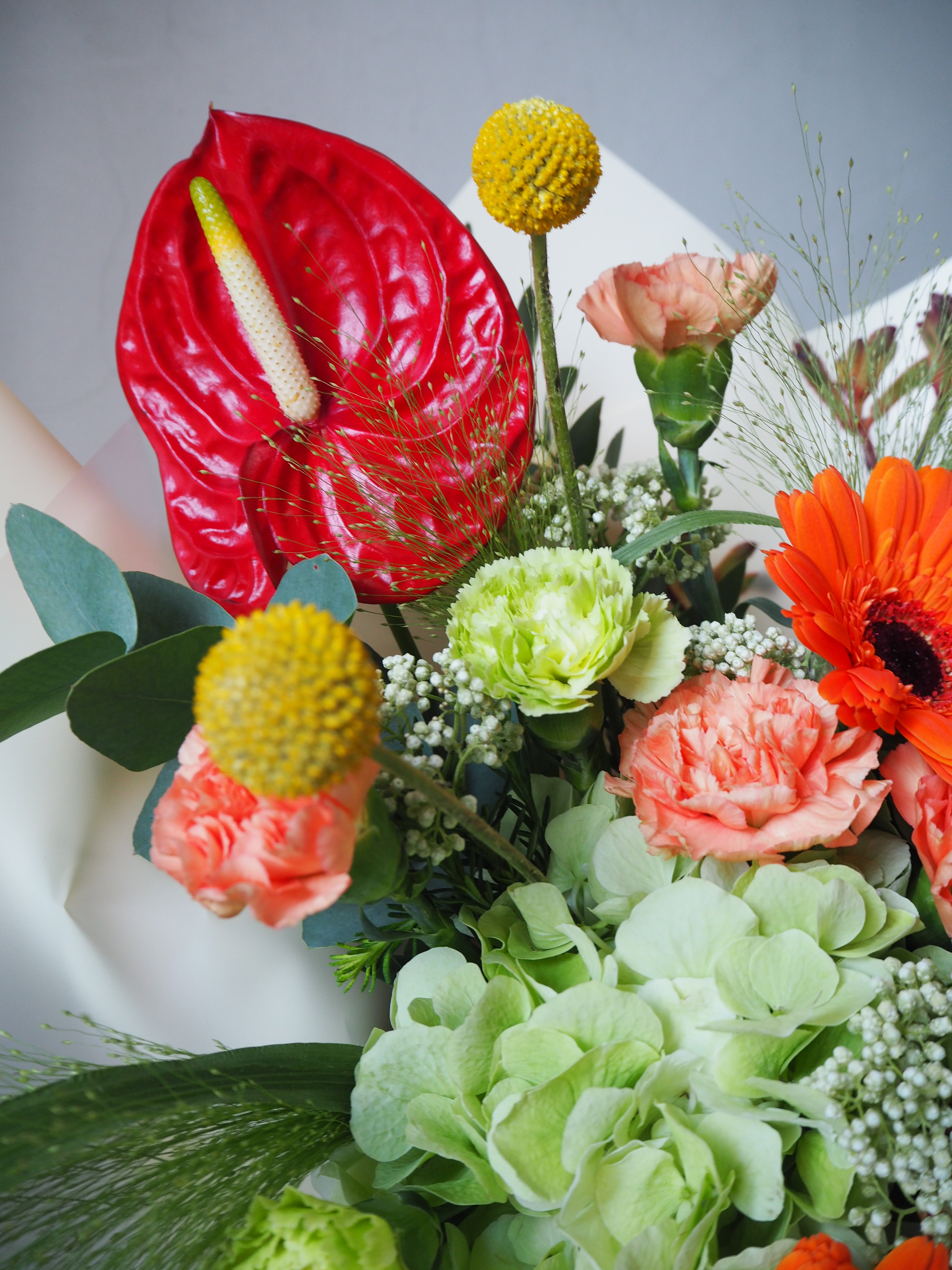 Bouquet of flowers with a red anthurium on a white surface