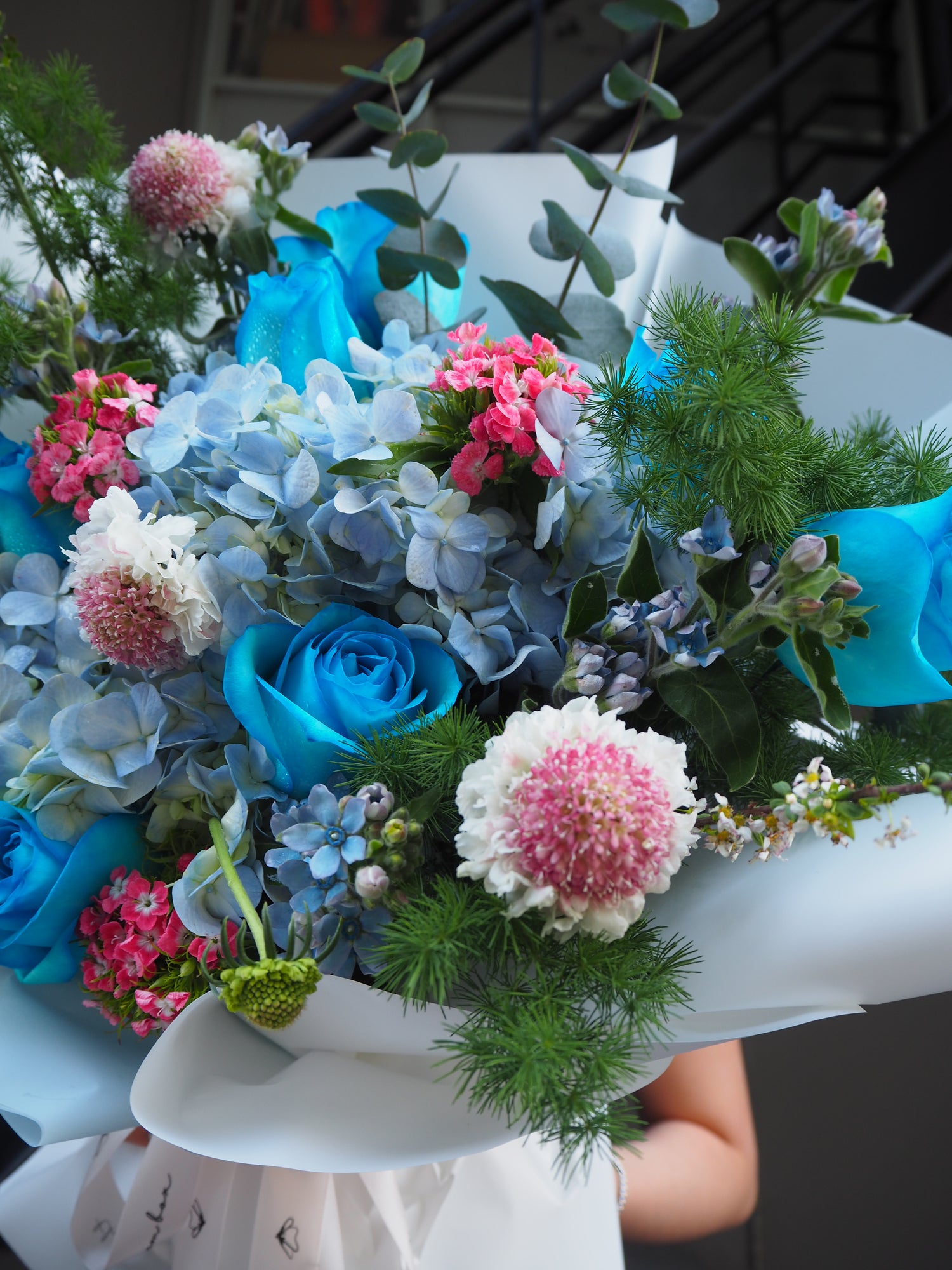 Beautifully crafted fresh flower bouquet with blue hydrangeas, blue roses and pink scabosia. 