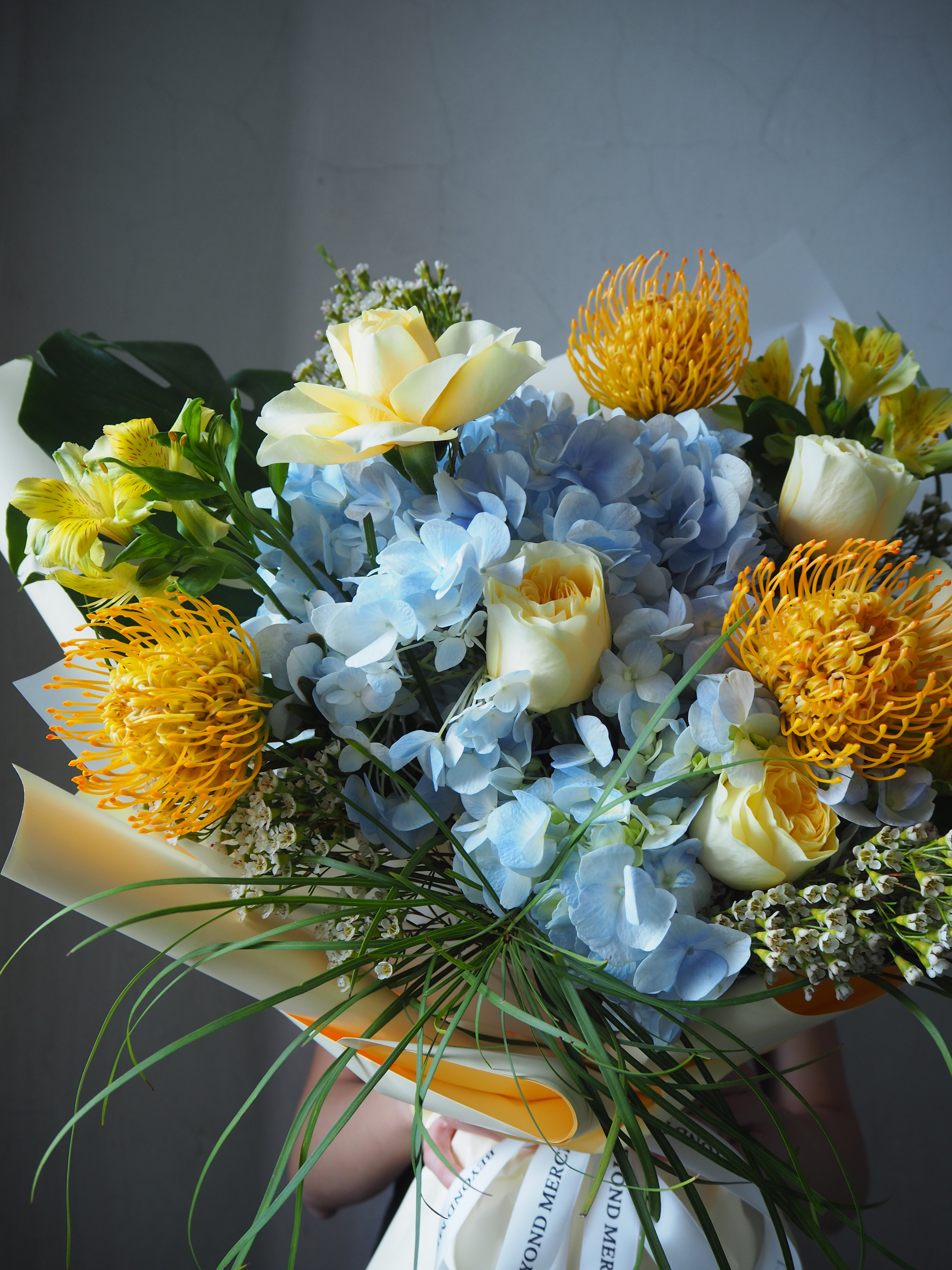 A fresh flower bouquet close up of blue hydrangea with yellow rose.