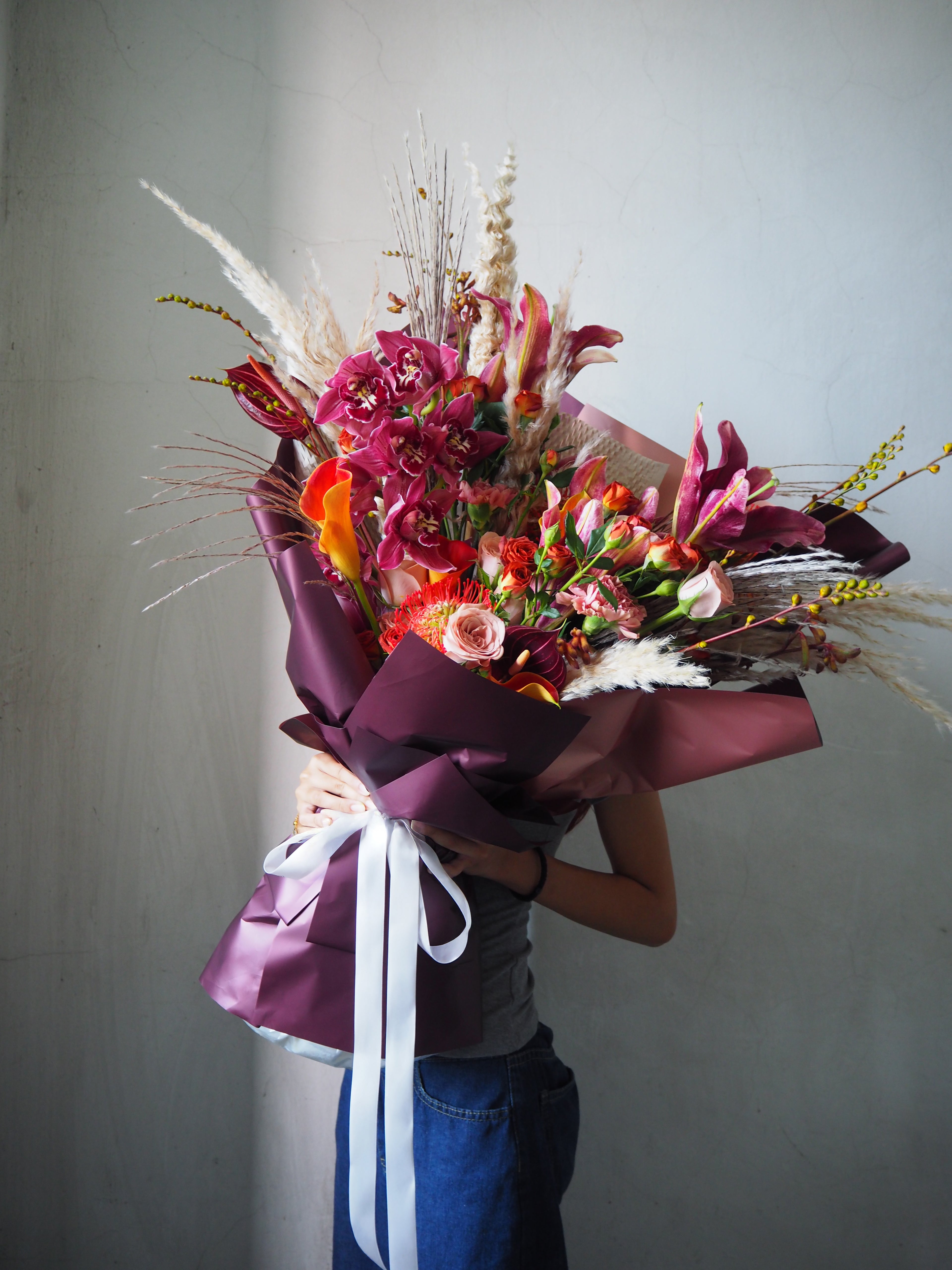 Person holding a vibrant bouquet of flowers against a plain background