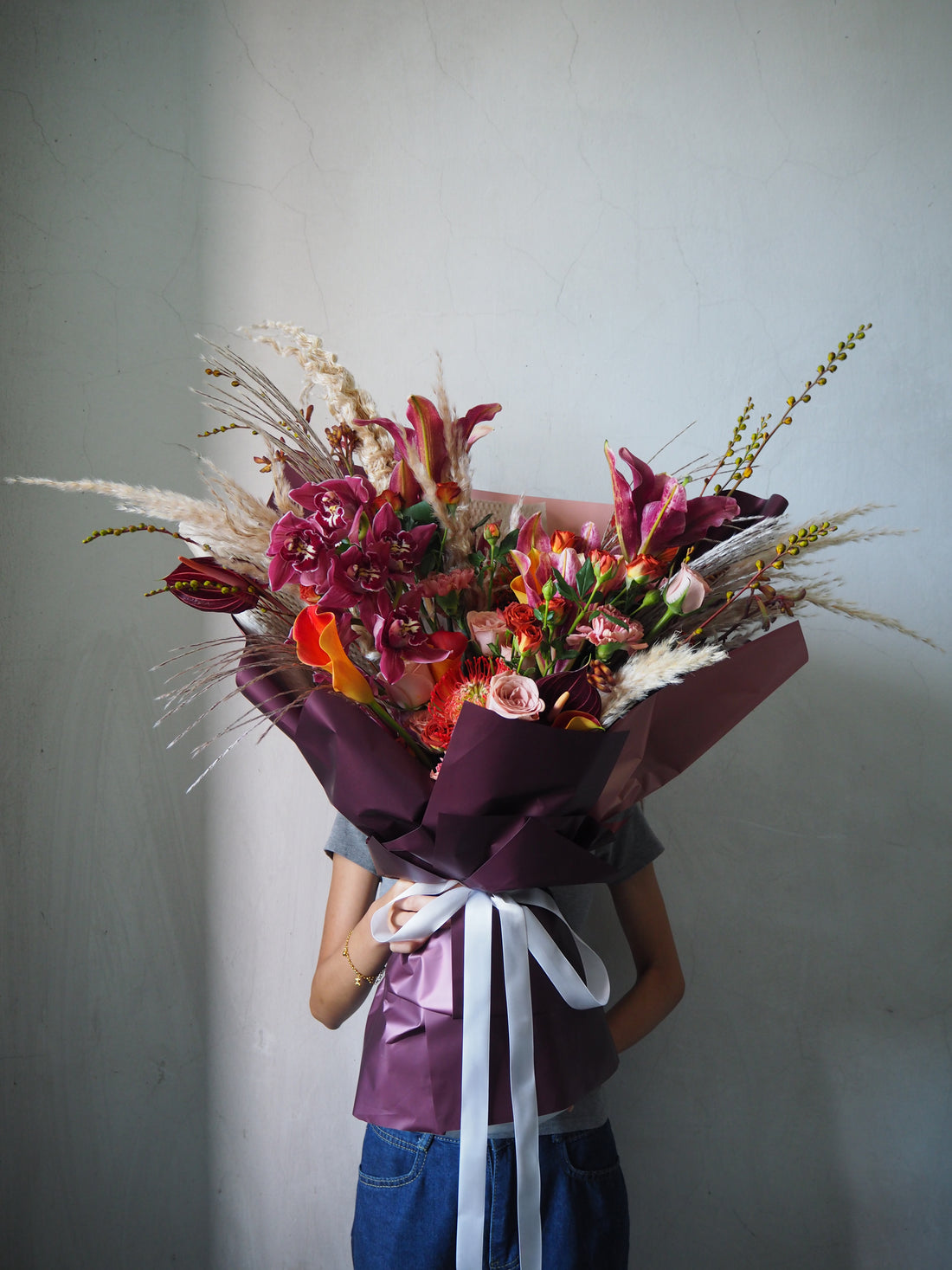 Person holding a vibrant bouquet of flowers against a plain background