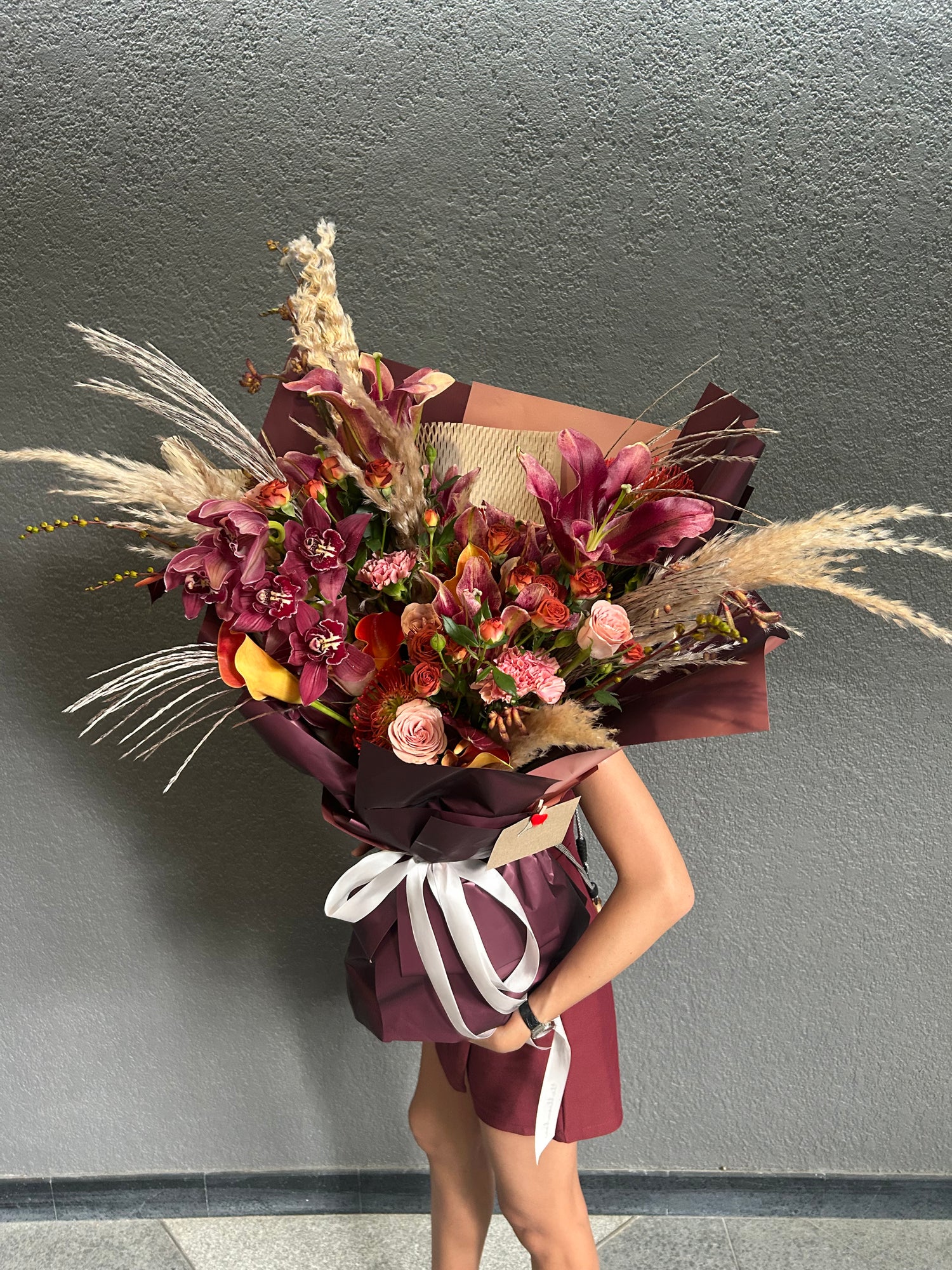 Person holding a bouquet of flowers against a gray wall