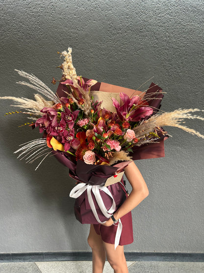 Person holding a bouquet of flowers against a gray wall